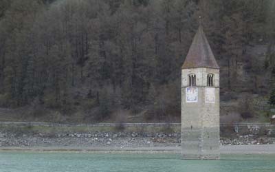 Mitten im Reschensee ragt ein Kirchturm aus dem Wasser. Er ist das Überbleibsel des Ortes Graun, dessen Ortsbewohner wegen des Stausees enteignet und umgesiedelt wurden.